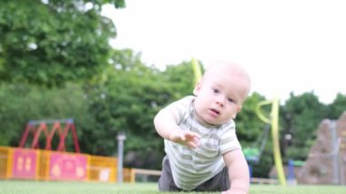 Mutlu aile piknik yapıyor. Küçük bebek yeşil çimlerde sürünüyor. Park yazında. Green Park 'ta oynayan kardeşler. Oyun salonunda aile eğlencesi ve neşe. Aktif oğul tarlada yalınayak sürünüyor..