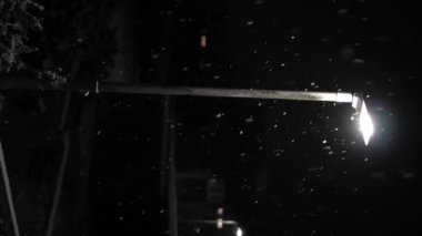 Birleşik Krallık 'taki ilk kar yağışı örtüsü kara arka planda. Gece Yolu 'ndaki Lambanın Işığında Düşen Kar Taneleri Kış, Yavaşça Düşen Kar Etkisi. Hava Durumu, Anomali, Acil Durum Konsepti.