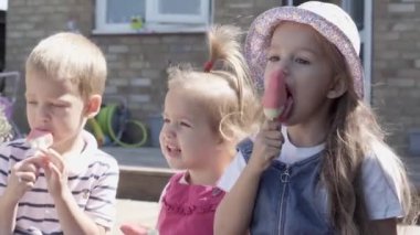Three cute little Children enjoys delicious ice cream cone. Child eating watermelon popsicle. Kids Siblings snack sweets in Home Garden. Summer holiday Hot weather Sunny Day. Childhood, Food Candy.