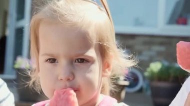 Close up portrait Girl enjoys delicious ice cream cone. Child eating watermelon popsicle. Kid Sibling snack sweets in Home Garden. Summer holiday Hot weather Sunny Day. Childhood, Food Candy Friends.