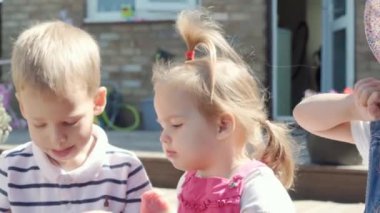 Three cute little Children enjoys delicious ice cream cone. Child eating watermelon popsicle. Kids Siblings snack sweets in Home Garden. Summer holiday Hot weather Sunny Day. Childhood, Food Candy.