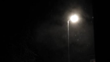 Birleşik Krallık 'taki ilk kar yağışı örtüsü kara arka planda. Gece Yolu 'ndaki Lambanın Işığında Düşen Kar Taneleri Kış, Yavaşça Düşen Kar Etkisi. Hava Durumu, Anomali, Acil Durum Konsepti.