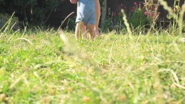 baby takes first steps in grass. mom walks with son in nature kid dream concept. baby takes first steps with mom. mom and little son feet baby close-up happy family Hot Summer