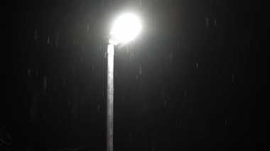 Birleşik Krallık 'taki ilk kar yağışı örtüsü kara arka planda. Gece Yolu 'ndaki Lambanın Işığında Düşen Kar Taneleri Kış, Yavaşça Düşen Kar Etkisi. Hava Durumu, Anomali, Acil Durum Konsepti.