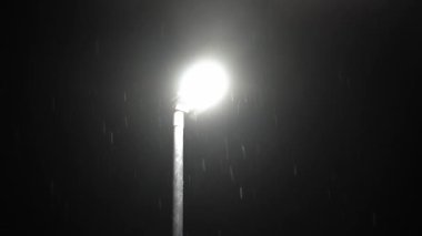 Birleşik Krallık 'taki ilk kar yağışı örtüsü kara arka planda. Gece Yolu 'ndaki Lambanın Işığında Düşen Kar Taneleri Kış, Yavaşça Düşen Kar Etkisi. Hava Durumu, Anomali, Acil Durum Konsepti.