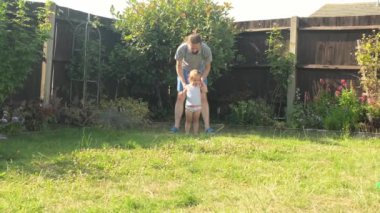 Baba ve küçük kızı güneşli yaz gününde oyun oynuyorlar. Babam sevimli küçük kızı kovalarken neşeli çocuk dışarıda gülüp eğleniyor. Çocukluk, aile kavramı.