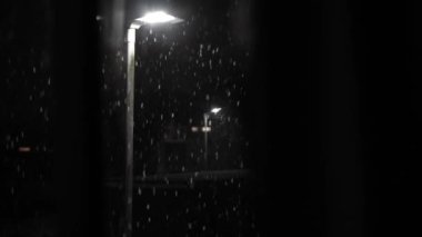 Birleşik Krallık 'taki ilk kar yağışı örtüsü kara arka planda. Gece Yolu 'ndaki Lambanın Işığında Düşen Kar Taneleri Kış, Yavaşça Düşen Kar Etkisi. Hava Durumu, Anomali, Acil Durum Konsepti.