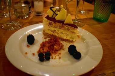 Passion meyve martinili cheesecake 'in yakın çekimi. Votka kaplı cheesecake, beyaz çikolatalı bal peteği nugget, beyaz tabakta vanilyalı dondurma..