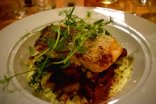 Yakın plan fırında kızartılmış deniz balığı kerevizi, haşlanmış pırasa, bebek yeni patates, dereotu ve beyaz şarap sosu..