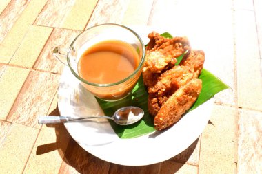 Sabah güneşinde bir fincan taze organik kahve ve beyaz tabakta kızarmış muz. Tayland 'ın bir kırsalında yavaş bir yaşam tarzı.