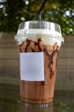 Bokeh ışıkları ve bulanık arka planda plastik bardakta buzlu çikolata karışımı..