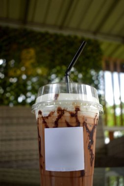 Thai çikolatası buzlu plastik bardakta, arka planda bulanık ışıklar ile sorunsuzca içilir..