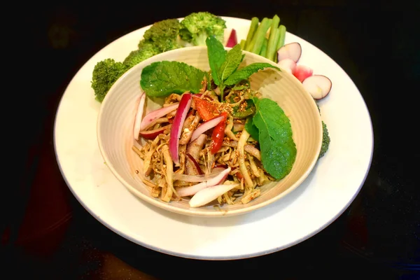 Spicy bamboo shoot salad Seasoning with mint leaves Red onion side dish with organic vegetables on black background. Local Thai food. North East Thai food (Yum Nor Mai)