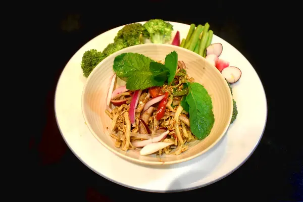 Spicy bamboo shoot salad Seasoning with mint leaves Red onion side dish with organic vegetables on black background. Local Thai food. North East Thai food (Yum Nor Mai)