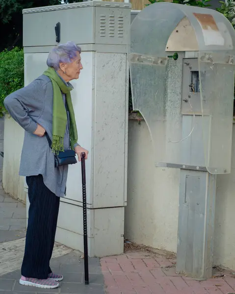 stock image Reflecting on the Years: Senior Woman Observes Dismantled Payphone, Contemplates Her Long Life