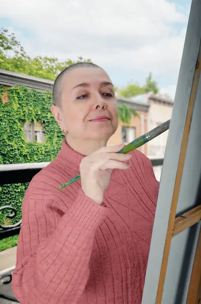 stock image Painting as therapy: A mature woman undergoing chemotherapy uses art to regain color perception and improve hand motor skills.