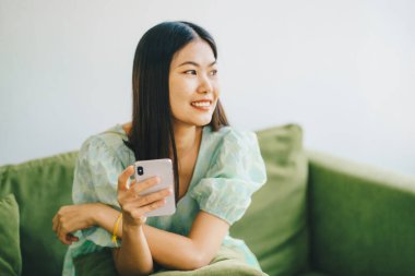 Yeşil koltukta oturan güzel, mutlu kadınlar akıllı telefonlar kullanıyor.