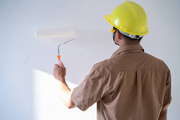 Painter man painting on white wall interior working new house with copyspace