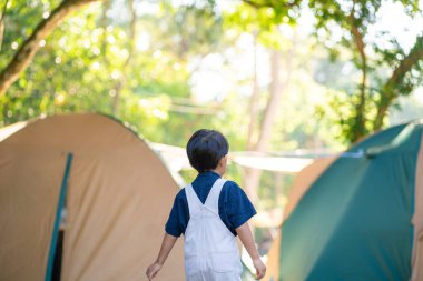 Happy little boy enjoying with adventure activity camping tent in green forest boy in nature