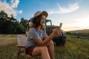 Asyalı kadınlar yaz tatili konseptiyle kamp yaparken akıllı telefon kullanırlar.