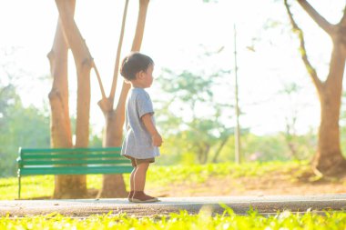 Boy walking on green grass in city park sunset light boy outdoor activity