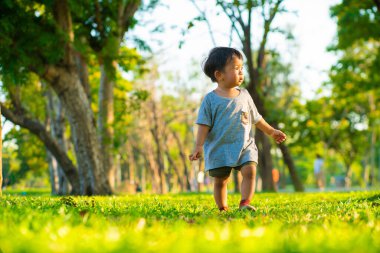 Boy walking on green grass in city park sunset light boy outdoor activity