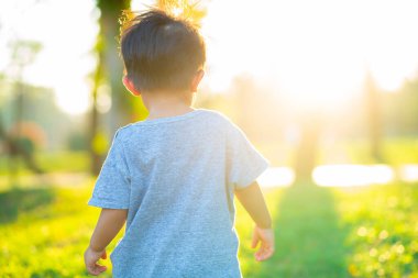 Boy walking on green grass in city park sunset light boy outdoor activity