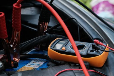 Mechanic man hand checking voltage of car battery maintenant transport industry concept