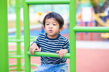 Neşeli Asyalı çocuk renkli oyun sahasındaki açık hava aktivitelerinde sıraya girer.
