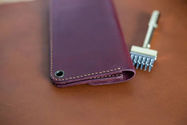 Leather phone and wallet bag working with tool on leather background craftmanship