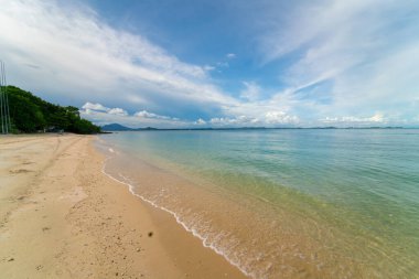 Deniz sahili dalgaları beyaz kumsalda mavi gökyüzü bulutlarına karşı yaz tatili