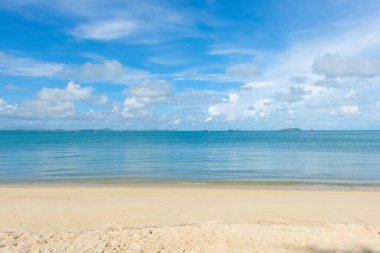 Deniz sahili beyaz kumu mavi gökyüzü bulutu sükunet sahnesi yaz tatili konseptine karşı dalgalandırıyor