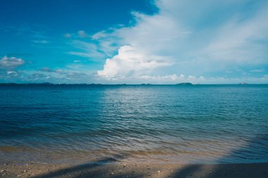 Deniz sahili beyaz kumu mavi gökyüzü bulutu sükunet sahnesi yaz tatili konseptine karşı dalgalandırıyor