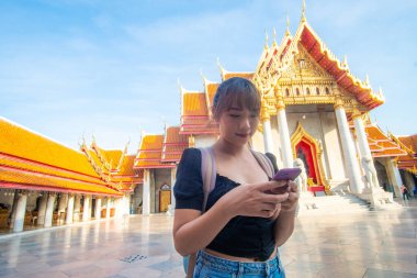 Sırt çantalı Asyalı kadınlar Bangkok Tayland 'da güneşli bir günde Busist tapınağında seyahat ederler.