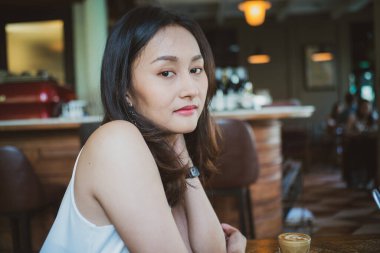 Güzel Asyalı kadın Bangkok Tayland 'da sıcak kahve içen klasik bir kafede oturuyor.