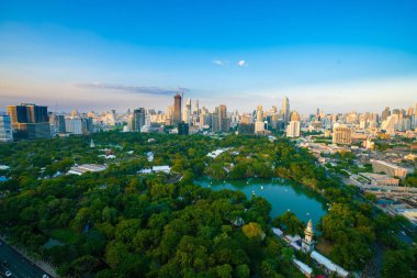 Bangkok şehrinde ağaç parkı olan modern ofis binası ve otel mavi gökyüzüne karşı Tayland bulutu