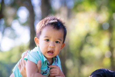 Baba, çocuğu elleriyle aldı. Parkta mutlu mesut eğleniyor.