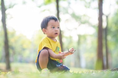 2 yaşındaki Asyalı çocuk yeşil çimen parkında oynuyor. Dışarıda rahatla.