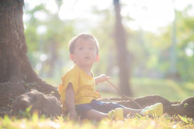2 yaşındaki Asyalı çocuk yeşil çimen parkında oynuyor. Dışarıda rahatla.