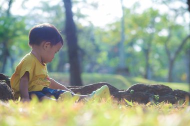 2 yaşındaki Asyalı çocuk yeşil çimen parkında oynuyor. Dışarıda rahatla.