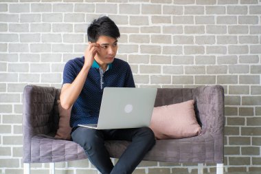 İnternette bilgisayarla çalışan Asyalı sıradan bir ofis elemanı odada oturuyor.