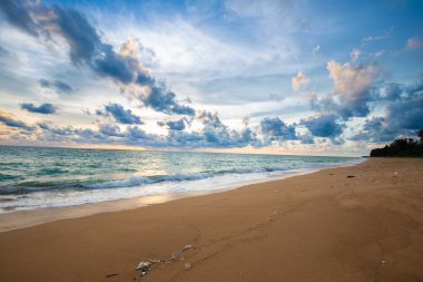 Deniz sahilinde bulutlu, güneşli bir gün batımı. Kum dalgası egzotik yaz tatili konsepti.