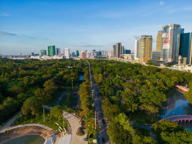 Green tree forest public park with city office building downtown of Bangkok Thailand