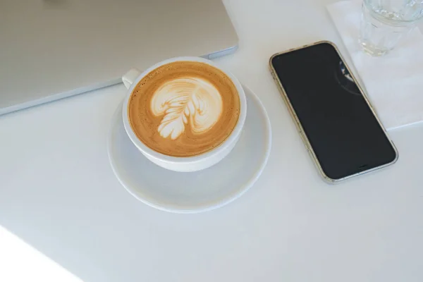 Beyaz Masadaki Sabit Nesne Üzerinde Telefon Dizüstü Bilgisayarlı Sıcak Latte — Stok fotoğraf