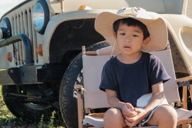 Mutlu Asyalı maceraperest çocuk dağ kamp tepesinde açık hava aktiviteleriyle eğleniyor.