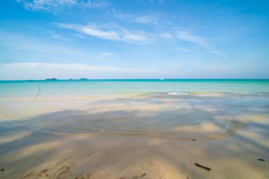 Deniz kıyısı dalgaları berrak turkuaz deniz suyu pürüzsüz kum mavisi gökyüzü bulutlu yaz tatili arka planı