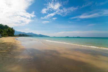 Deniz kıyısı dalgaları berrak turkuaz deniz suyu pürüzsüz kum mavisi gökyüzü bulutlu yaz tatili arka planı