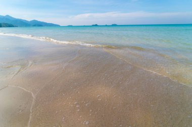 Deniz kıyısı dalgaları berrak turkuaz deniz suyu pürüzsüz kum mavisi gökyüzü bulutlu yaz tatili arka planı