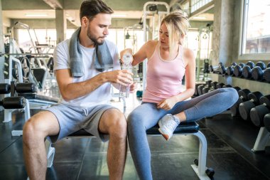 Spor salonunda egzersiz yaptıktan sonra su içen mutlu çift. Mutlu bir ilişki.