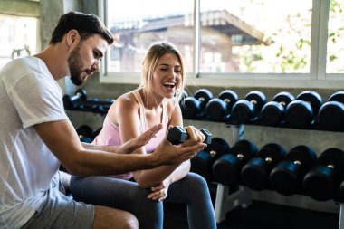 Erkek ve kadın, Fitnes Spor Salonu 'nda dambılla çalışıyor. Erkek arkadaşıyla spor yapıyor.